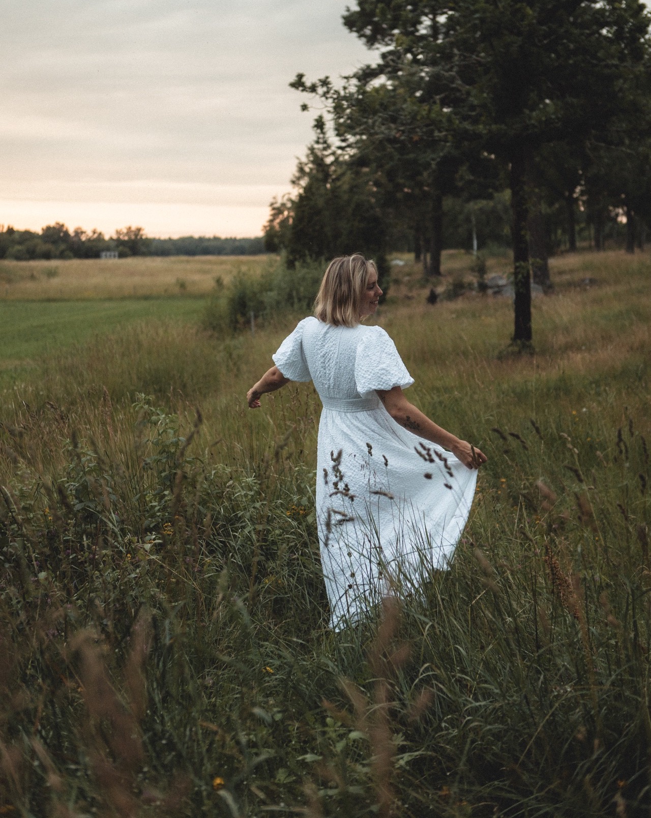 Kvinna i vit klänning i ängen i solnedgången på Vild & Fri-retreatet
